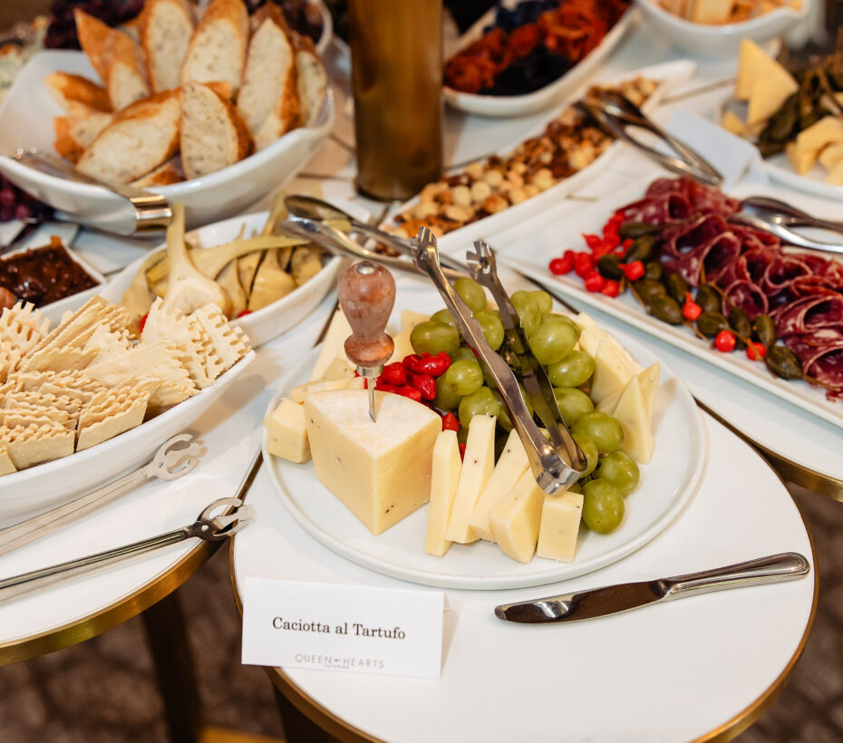 A cheese and charcuterie table with sliced bread, crackers, cheeses, grapes, and cured meats.